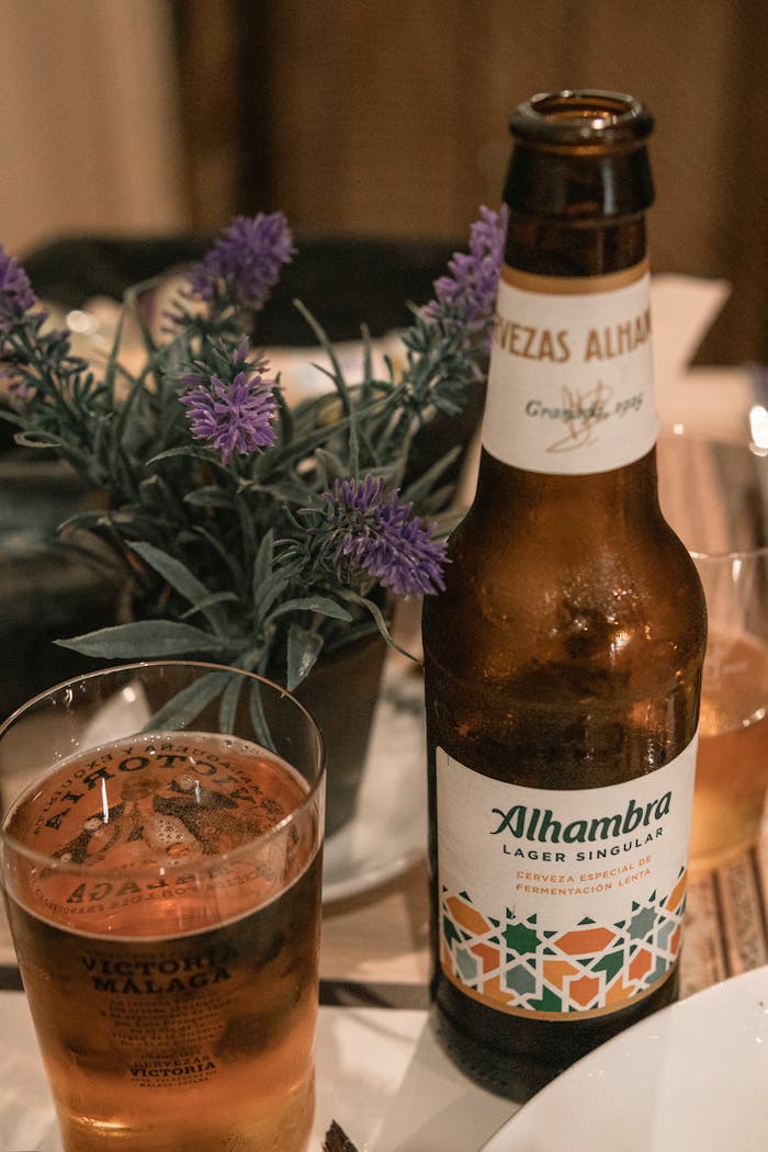 Close-up of Alhambra Lager Singula in a beer bottle and glass, with a potted plant.