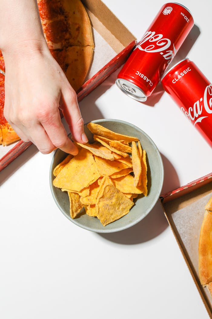 Top view of pizza, chips, and cold Coca-Cola. Ideal for fast food themes.